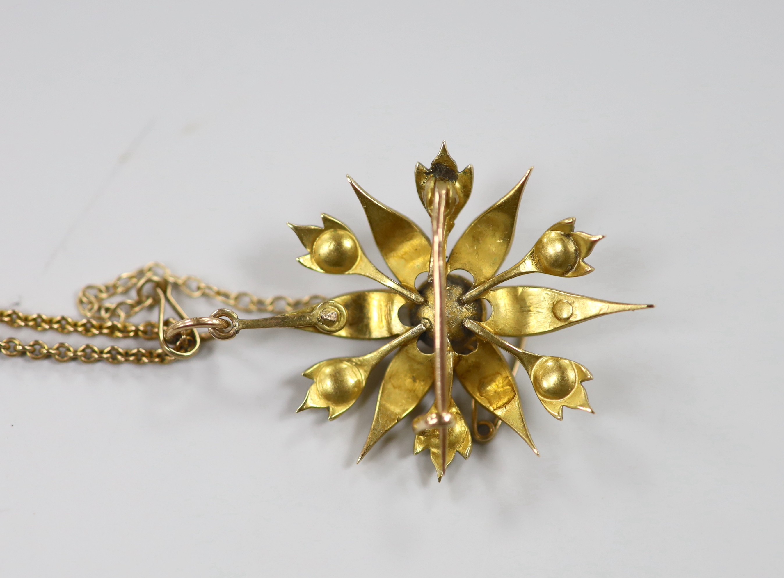 An Edwardian yellow metal and split pearl cluster set starburst pendant brooch, 37mm, on a later 9ct chain, 40cm, gross weight 9.6 grams.
